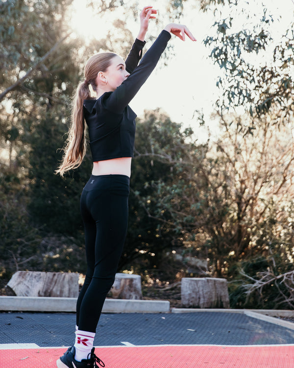 Tween stretching outdoors on a red surface with trees in the background