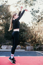 Tween stretching outdoors on a red surface with trees in the background
